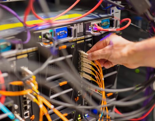 Closeup of IT consultant connecting network cable into switch in datacenter